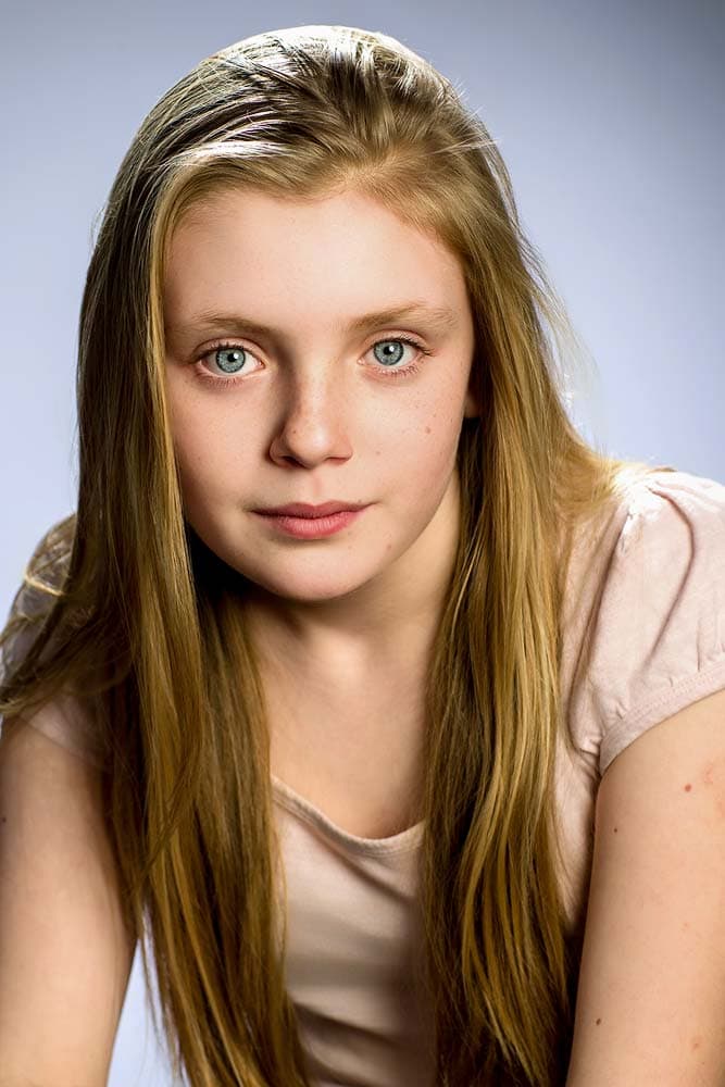 Beautiful portrait of a young girl with long red hair, blue eyes, and natural makeup, perfect for professional headshots and modern Sussex photography.