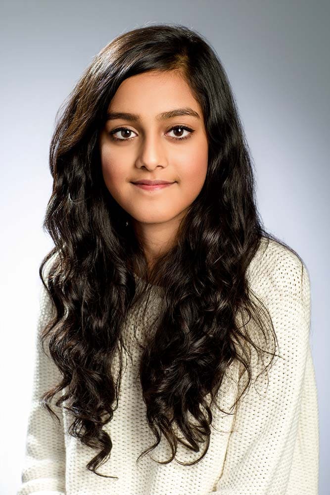 Professional headshot of a young woman with long, dark curly hair for corporate or branding photoshoots in Sussex.