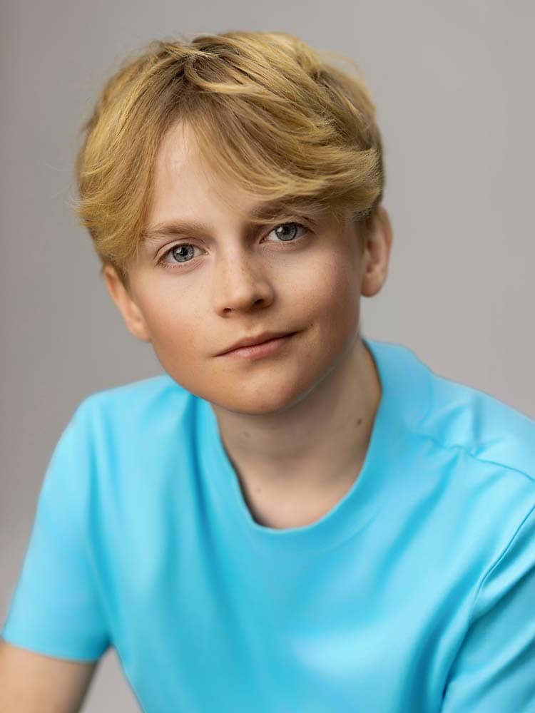 Natural headshot of a young man with blonde hair and blue eyes, wearing a blue t-shirt, showcasing professional Sussex headshots and portrait photography services.