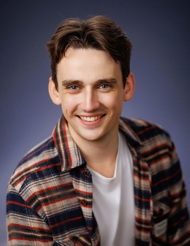 Actor headshots in Sussex. Professional headshot of a young man in casual plaid shirt, showcasing confident and approachable personality for corporate and personal branding photography in Sussex.