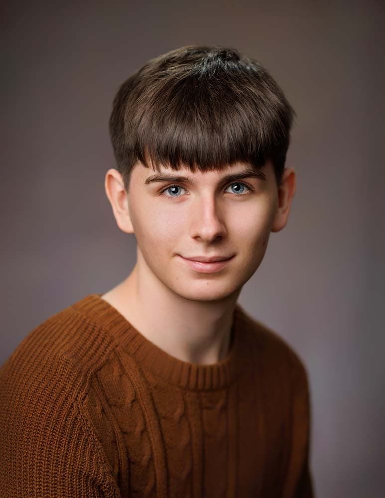 Professional Sussex headshot of a young man with blue eyes and brown hair, wearing a rust-coloured sweater, ideal for corporate and personal branding.