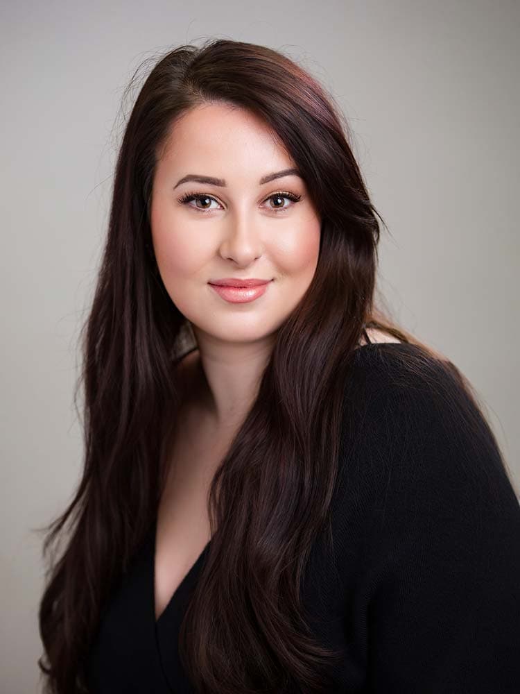 Confident Crawley headshots. Female headshot of woman with long brown hair, professional makeup, and a black blazer for corporate headshots and personal branding in Sussex.