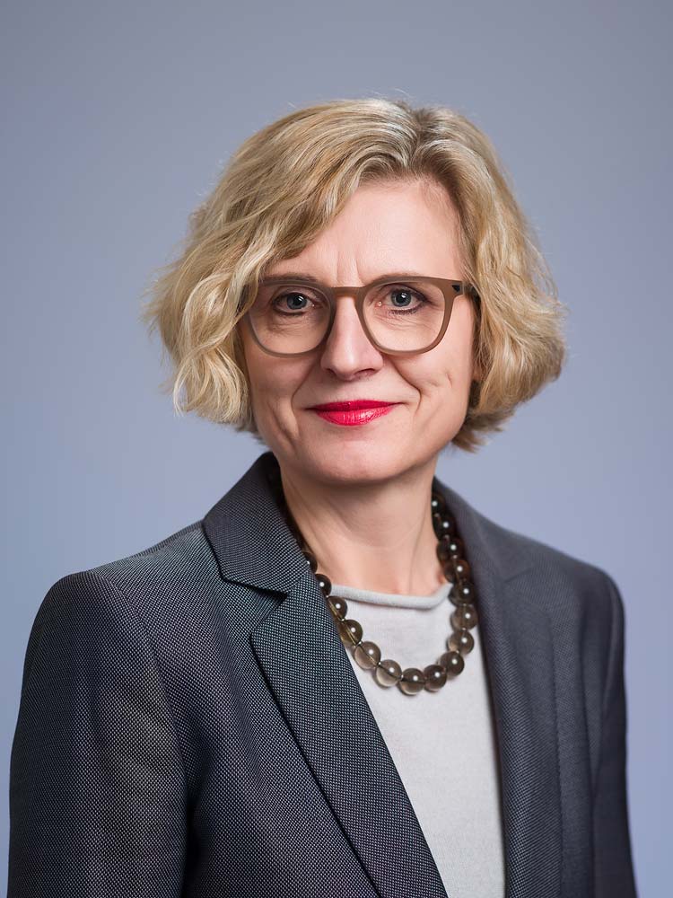 Sussex headshot professional woman in business attire with blonde hair and glasses for corporate profile shots.
