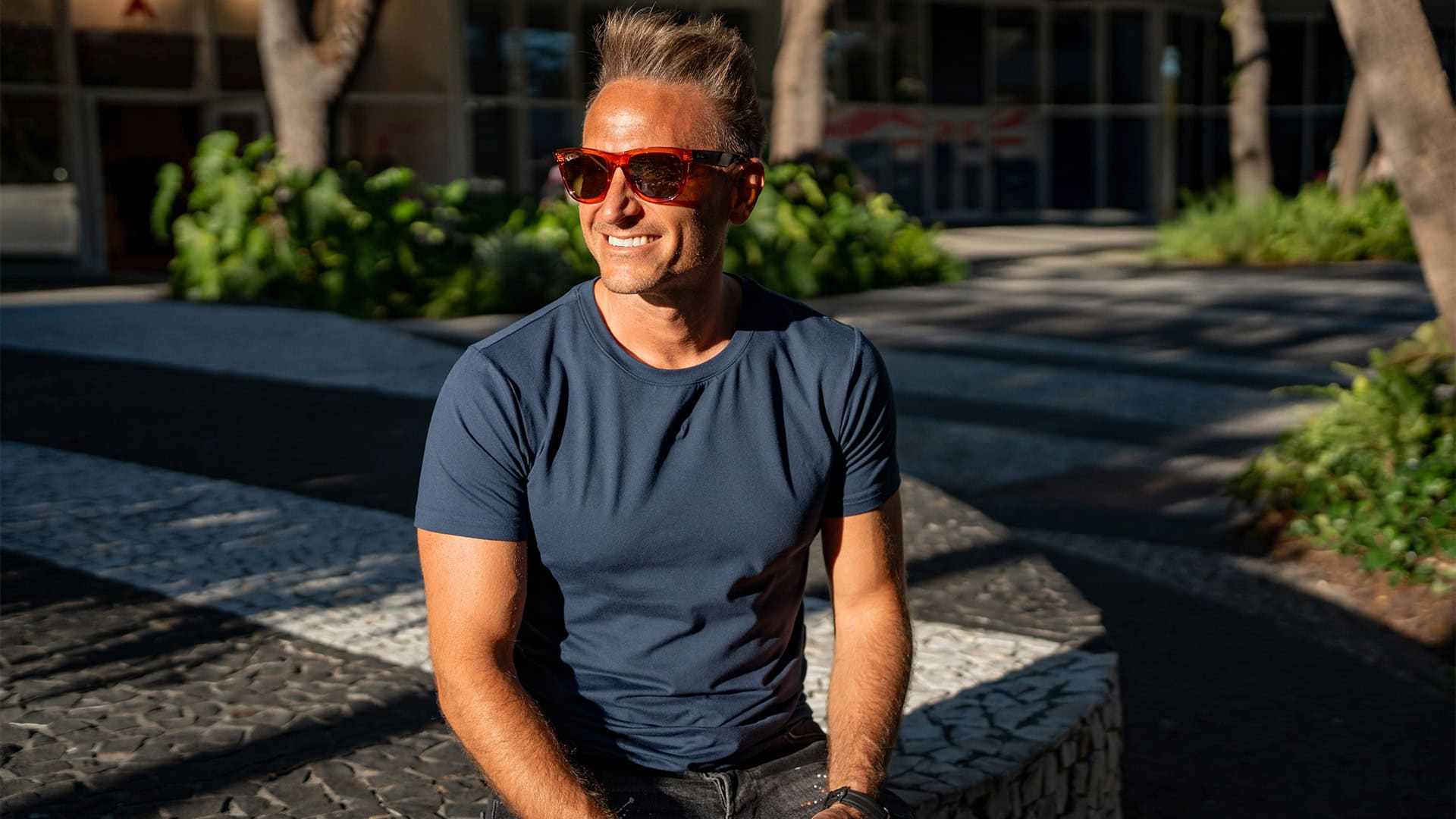 Innovative venture capitalist smiling outdoors, wearing sunglasses and casual attire, representing advanced investment solutions and entrepreneurial success.