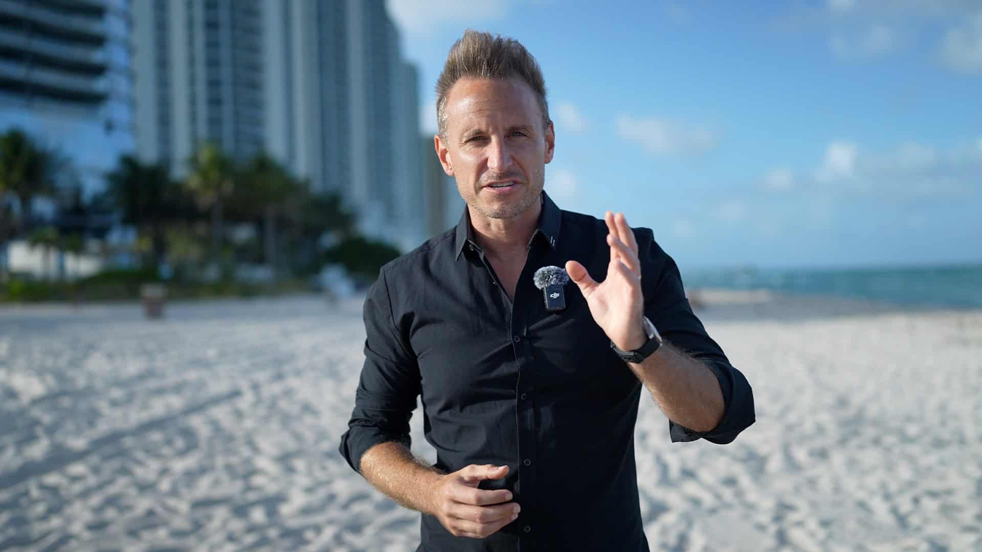 Professional male videographer filming on beach with high-end camera equipment for content creation.