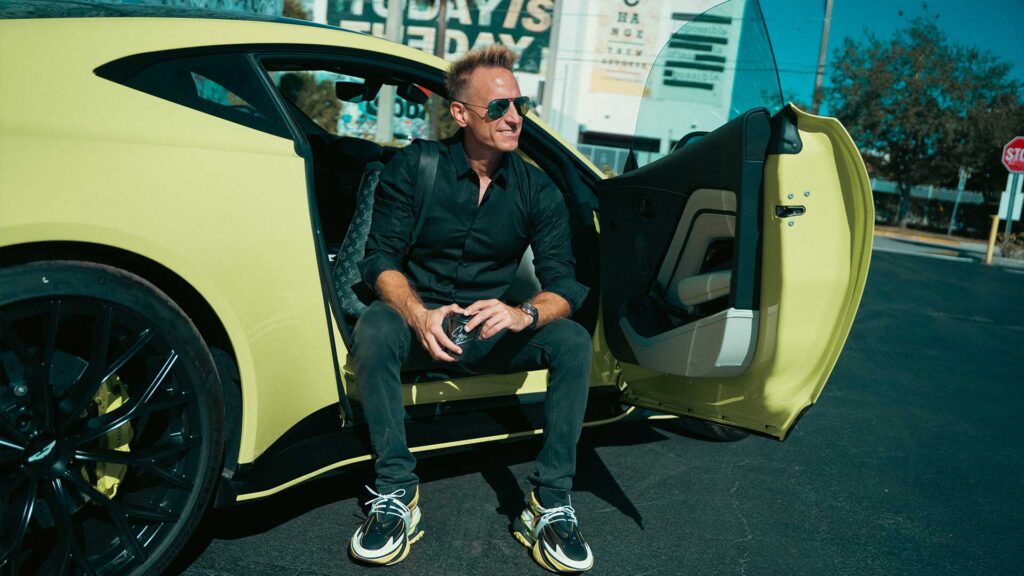 Luxury electric vehicle, man sitting in yellow sports car, modern eco-friendly transportation, stylish man with sunglasses, high-performance EV.