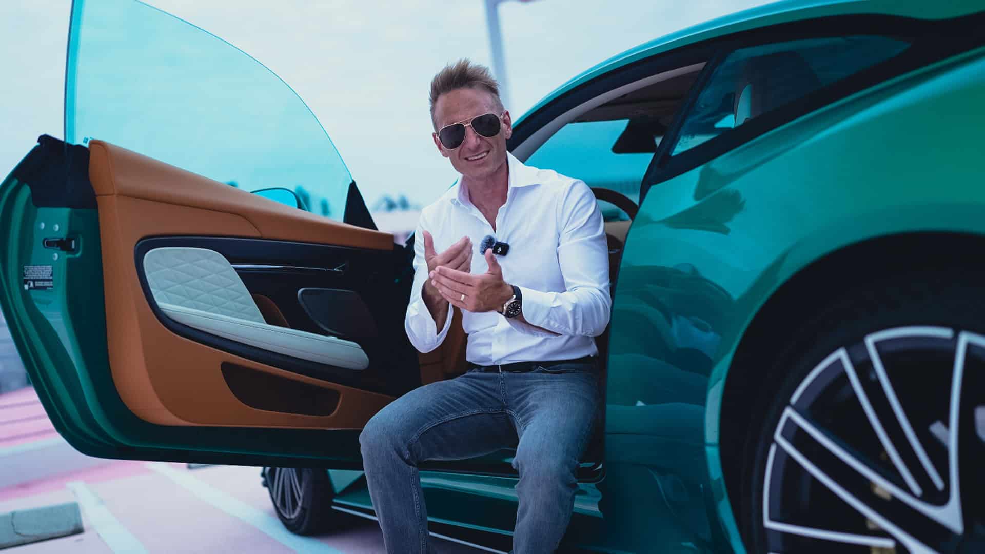 Luxury electric vehicle owner showcasing car features at a dealership or event.