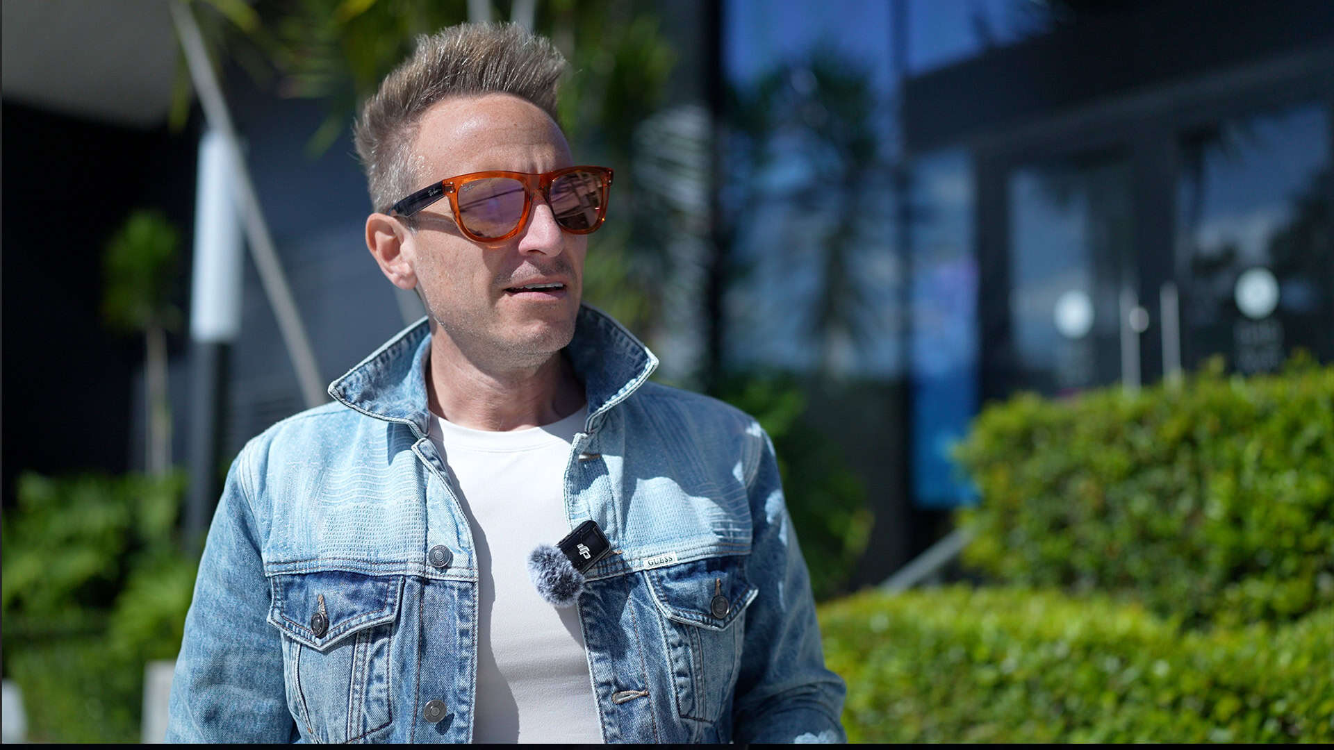 Fashionable man wearing sunglasses and denim jacket in outdoor setting at Syslo Ventures headquarters.