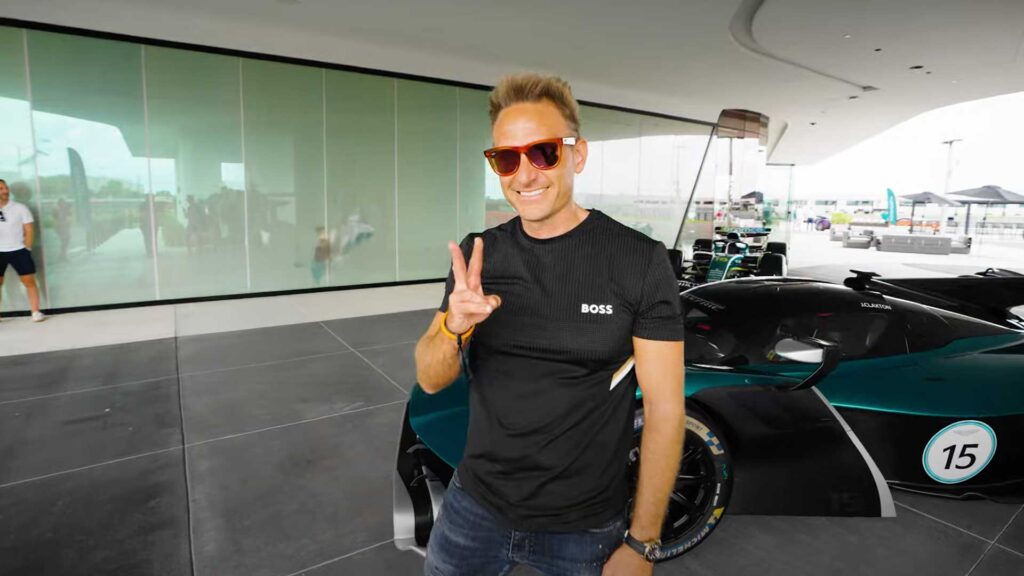 Luxury sports car and smiling man in sunglasses at a modern racing facility, showcasing innovative automotive design and high-performance vehicles for premium car enthusiasts.