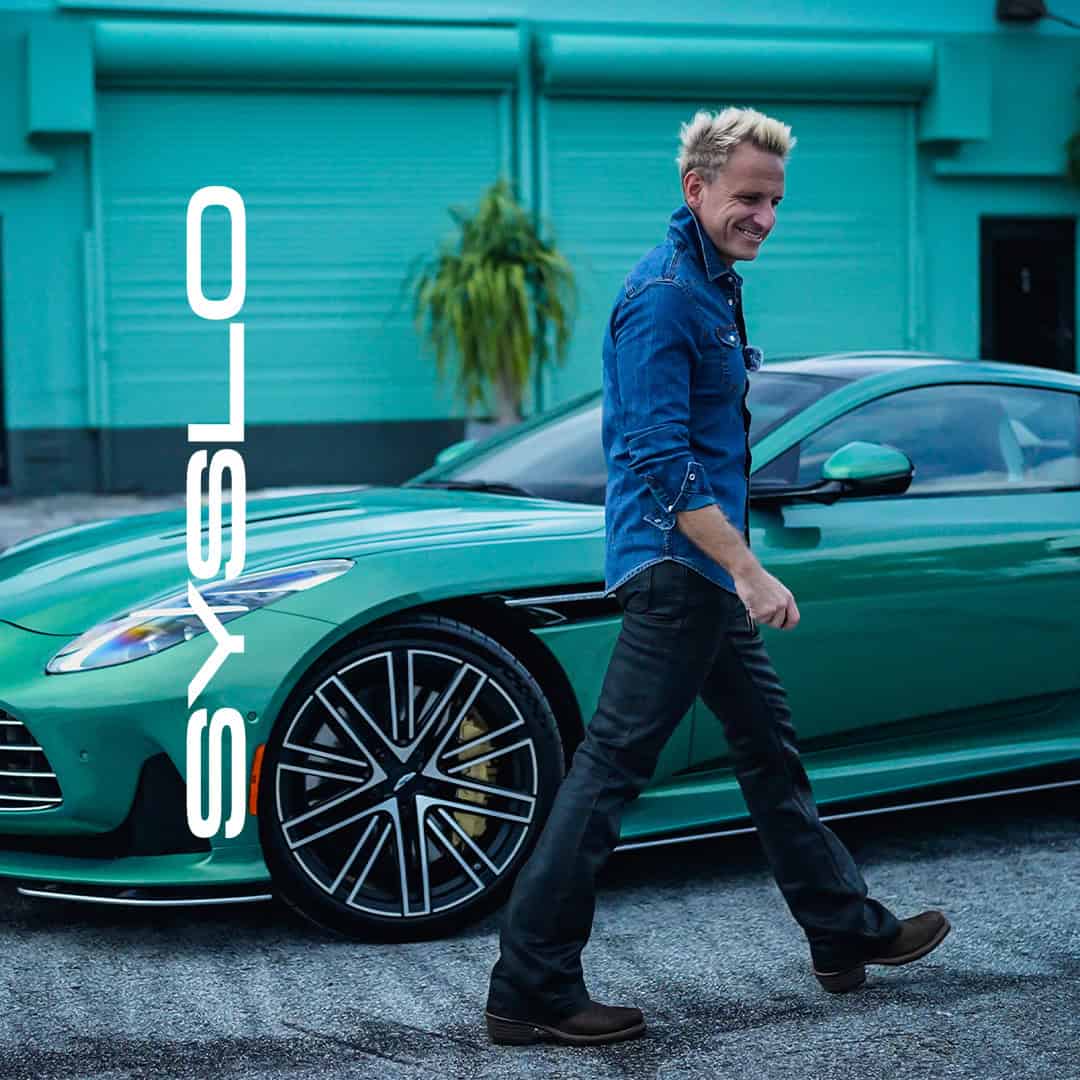 Green sports car parked outdoors, smiling man in denim shirt walking beside vehicle, luxury automobile, modern design, luxury lifestyle, automotive, executive transportation, vehicle, affluent, stylish, syslo ventures branding, business success.