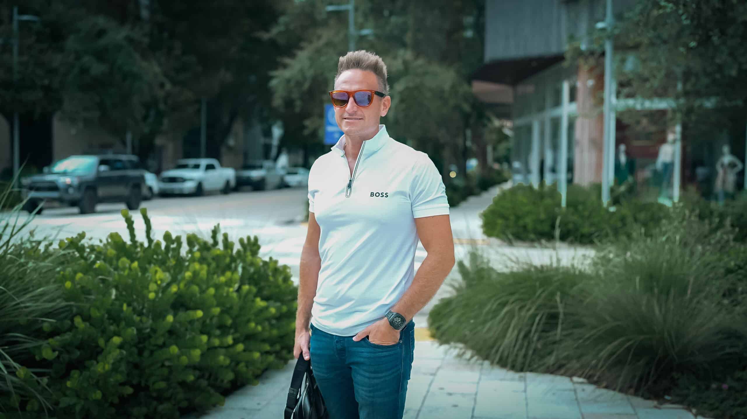 Stylish man in casual business attire with sunglasses and a wristwatch, standing outdoors in an urban environment, representing professionalism and modern lifestyle for Syslo Ventures.