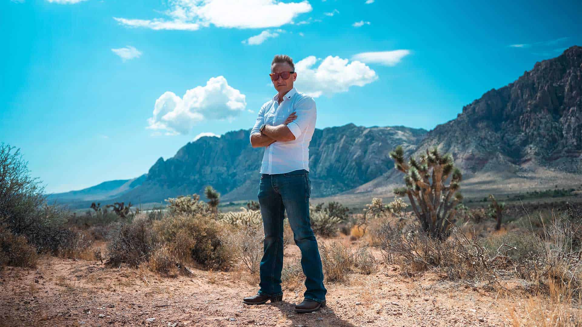 Vast desert landscape with rugged mountains, Joshua trees, and a clear blue sky, symbolizing adventure, resilience, and entrepreneurial spirit for Syslo Ventures.