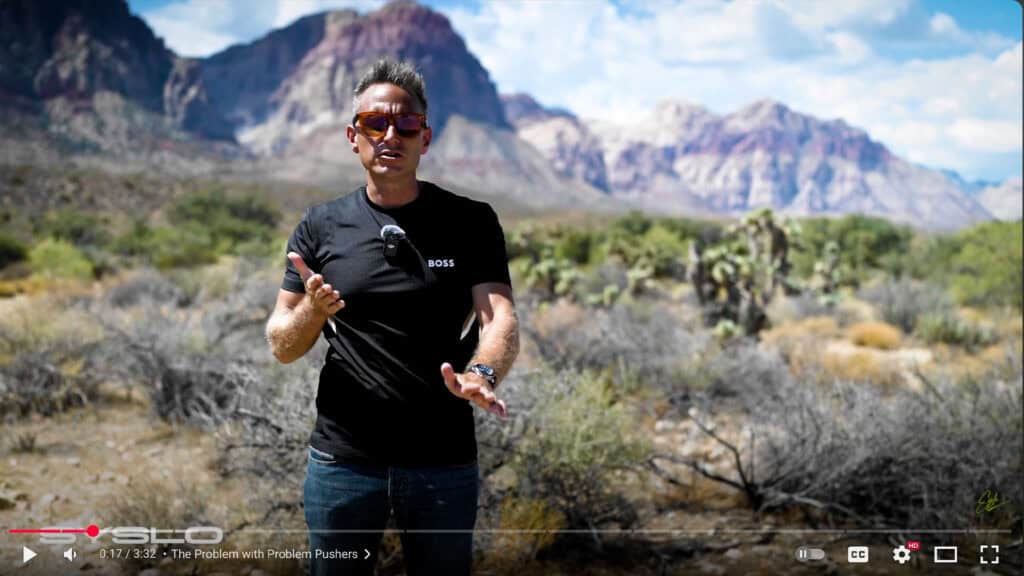 Innovative entrepreneur speaking outdoors in desert landscape with mountains, emphasizing startup solutions, business growth, and entrepreneurial challenges.