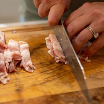 chef knife slicing bacon into strips