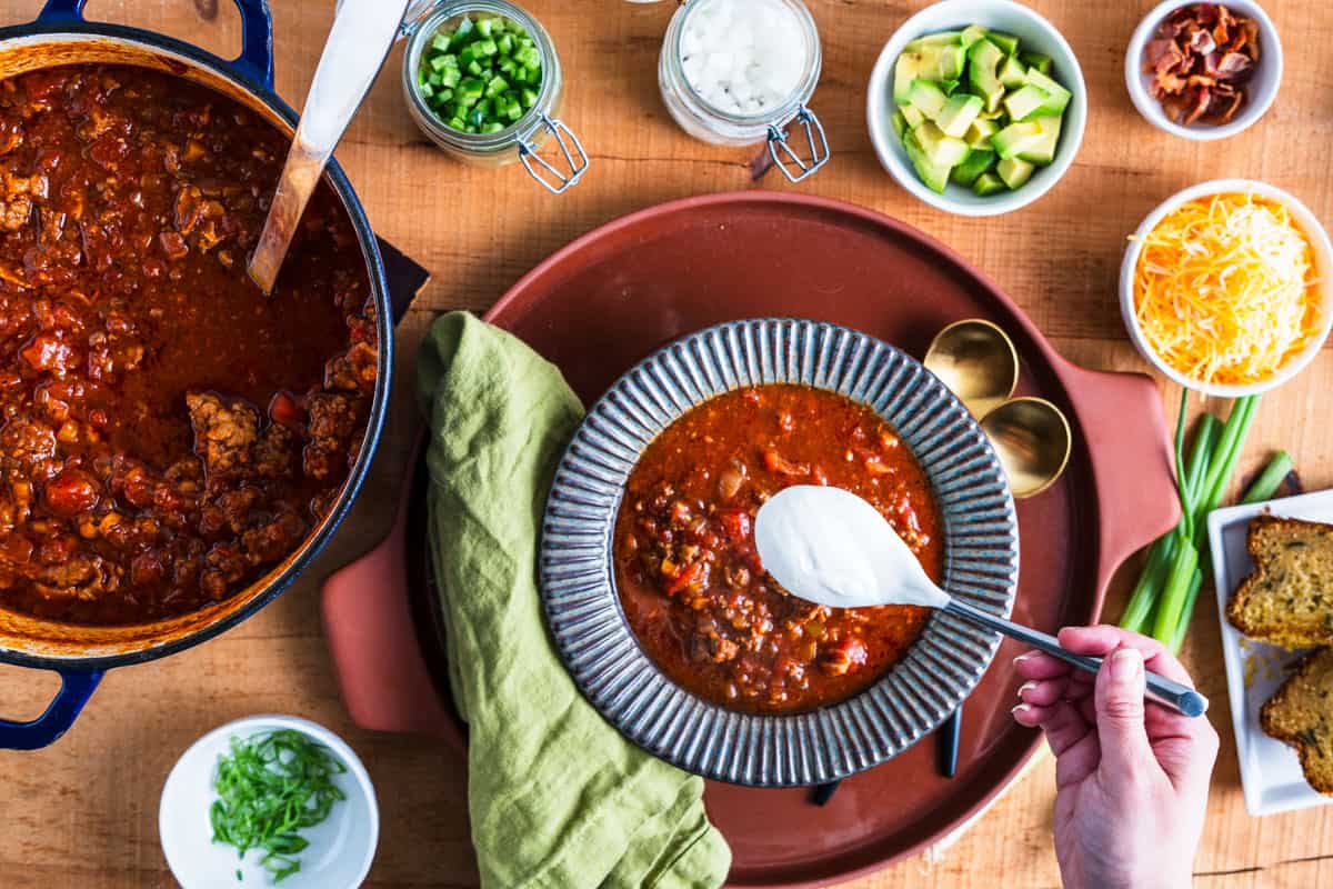 a spoonful of sour cream overtop of a bowl of chili