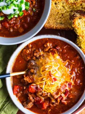 bowl of chili with cheddar cheese and bacon on top