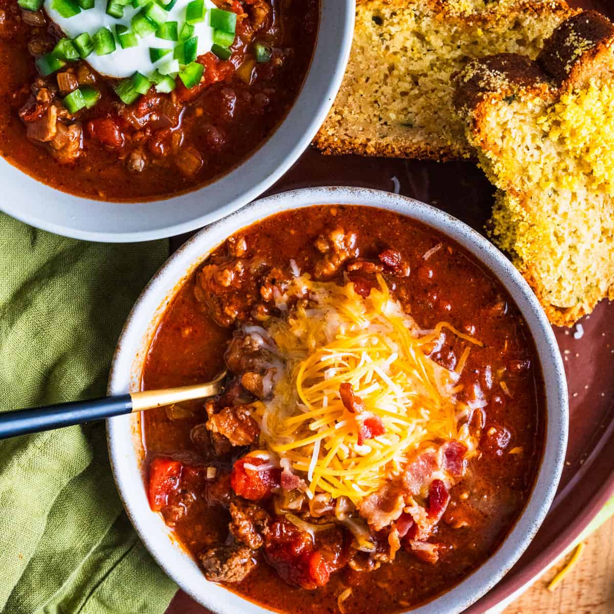 bowl of chili with cheddar cheese and bacon on top