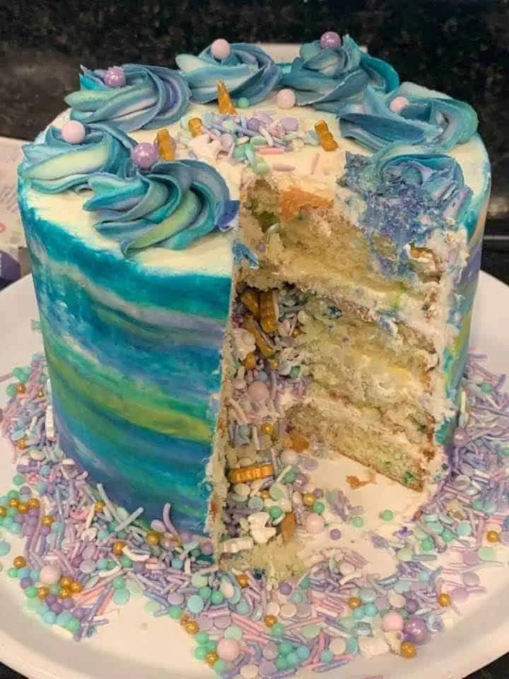 Sliced paint splatter cake showing rainbow funfetti sprinkles inside white vanilla cake