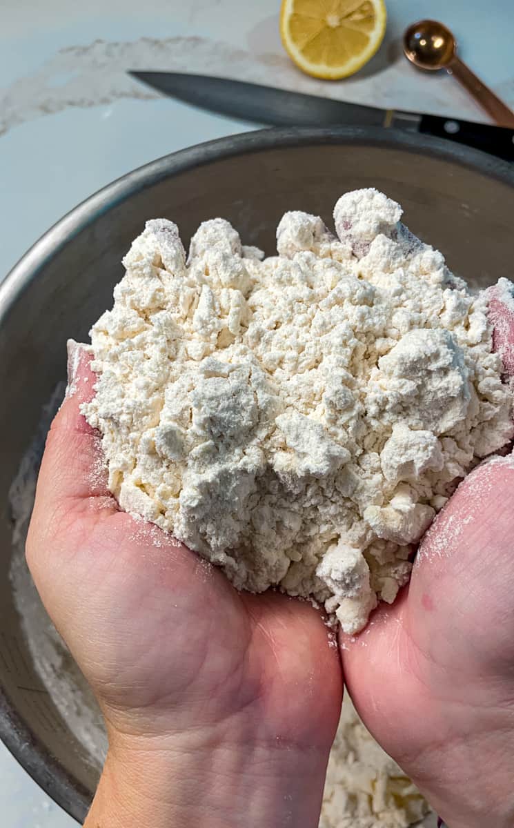 Shaggy Pastry Dough being held between two hands for pate brisee