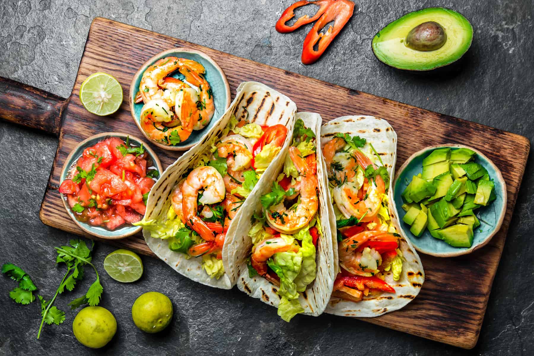 Cilantro lime tacos on a wooden board surrounded by toppings