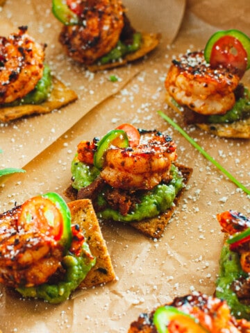 Shrimp and guacamole on top of a spicy pita chip garnished with cojita cheese