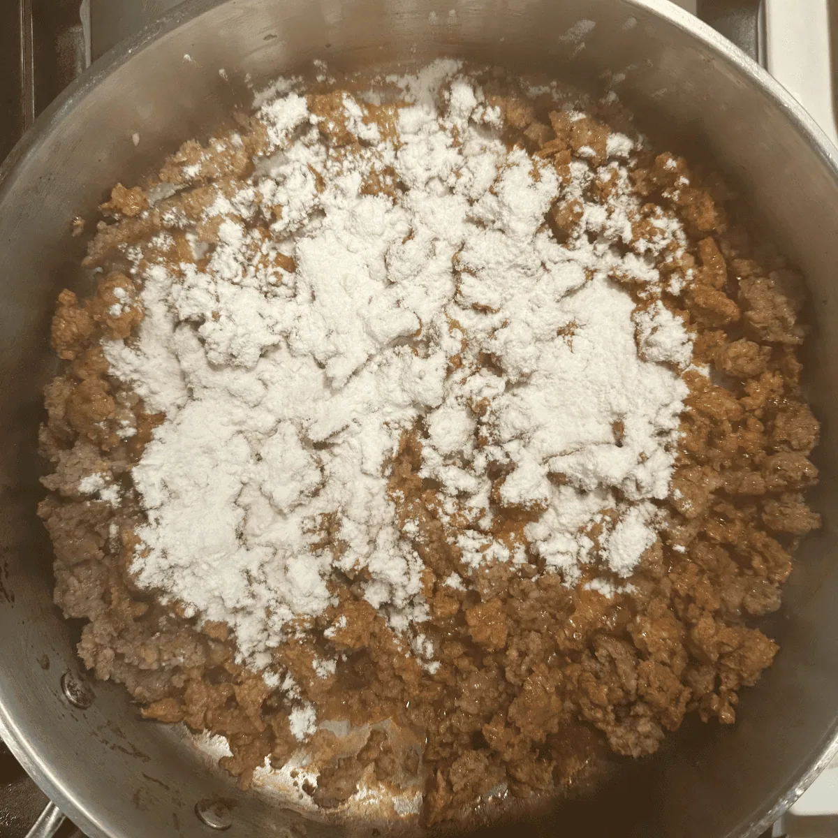 Flour being added on top of browned chorizo
