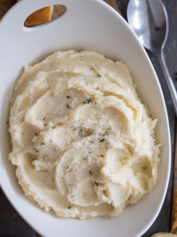 Parmesan Mashed Potatoes in a bowl garnished with fresh parm and thyme