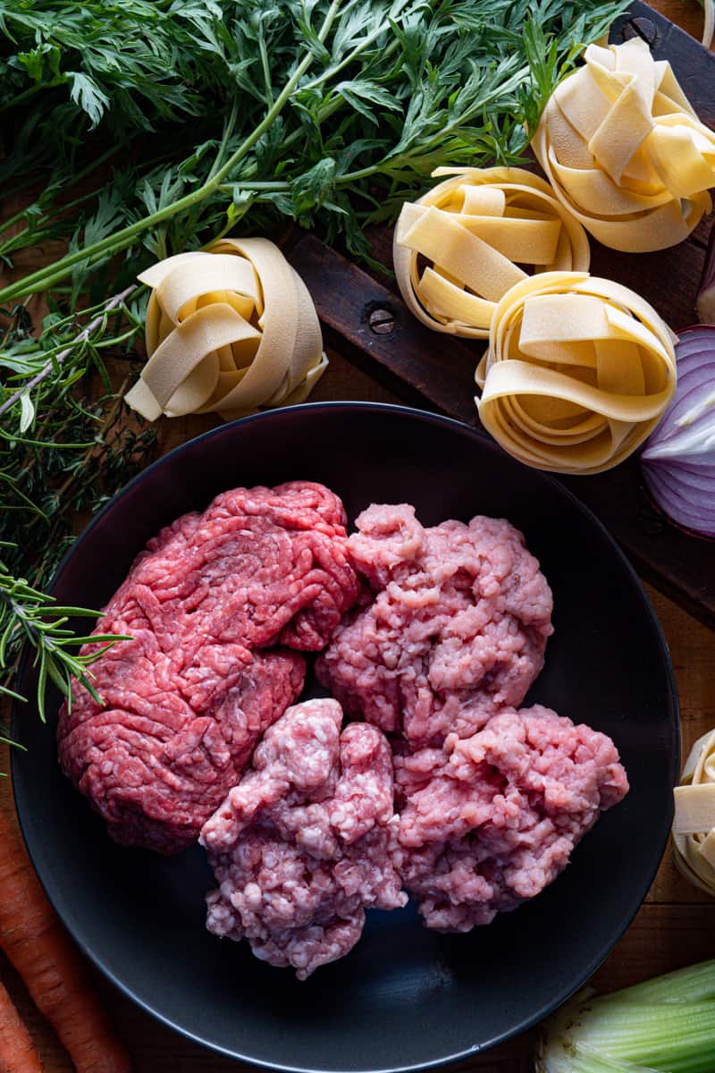 ground beef and pork in a bowl with dried pasta nest on a table