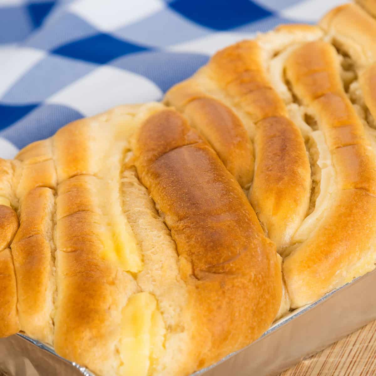 Brioche load in the pan with a blue and white checkered napkin