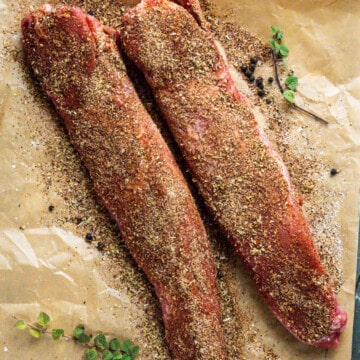 Two pork tenderloins covered in a spice blend prior to cooking