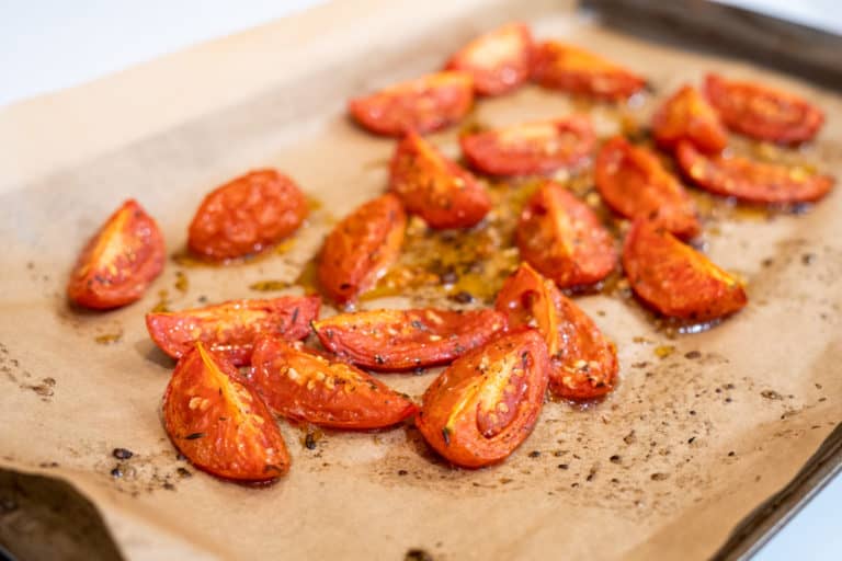 Roma tomatoes quartered on a sheet tray