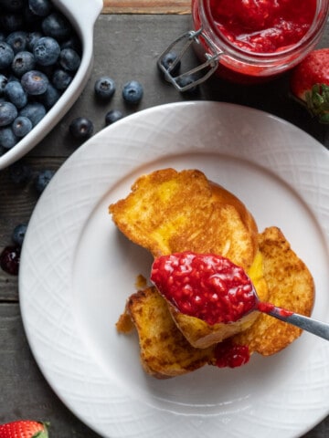 Raspberry compote being spooned onto brioche toast