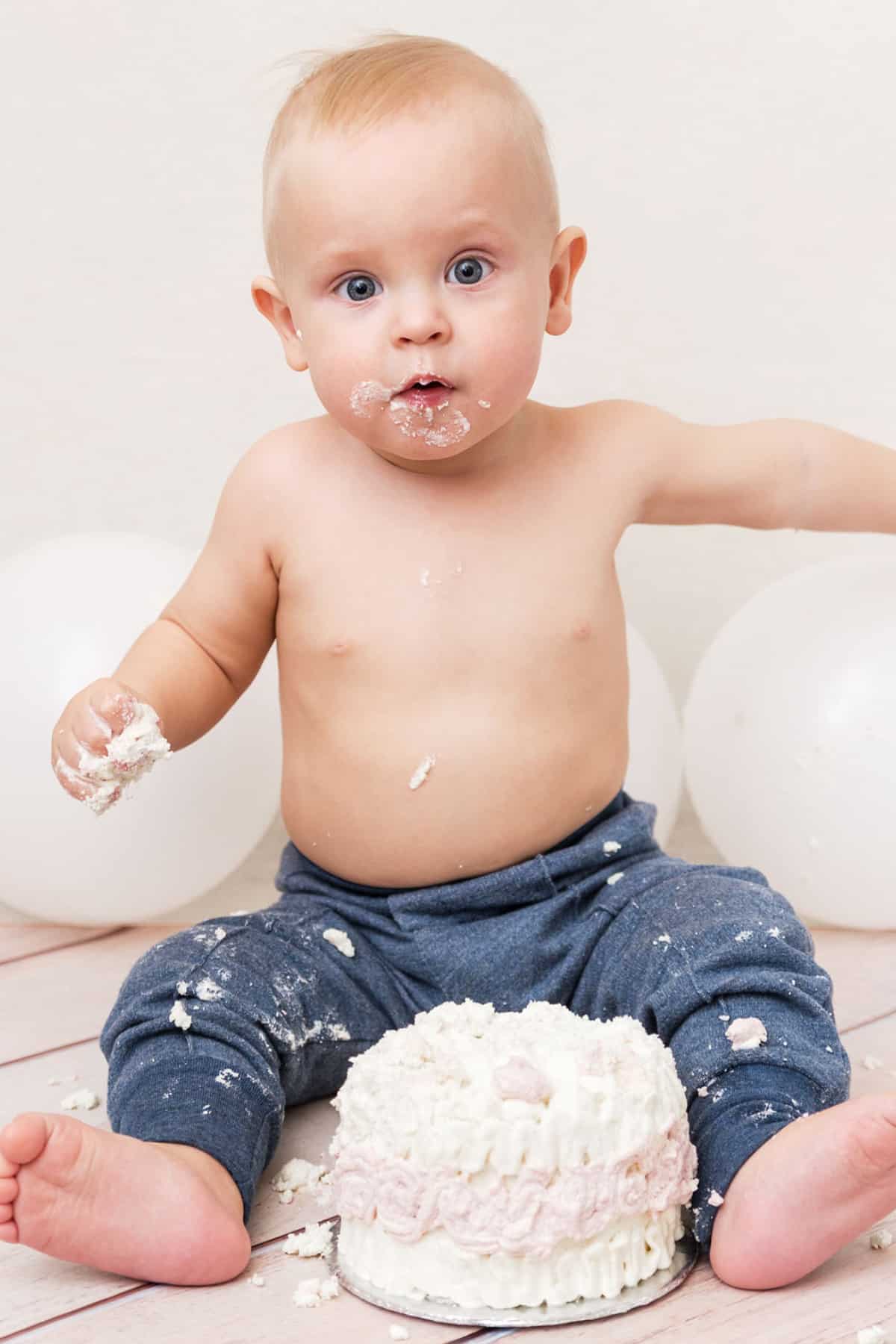 Baby sitting on the floor in front of a 4" smash cake