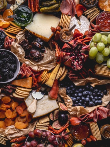abundant charcuterie spread with cured meats, cheeses, grapes, and crackers on a large board