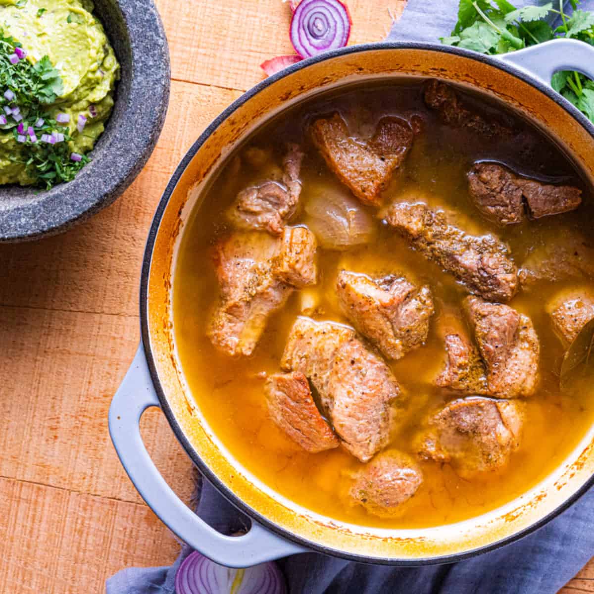 overhead view of carnitas reheating in a dutch oven