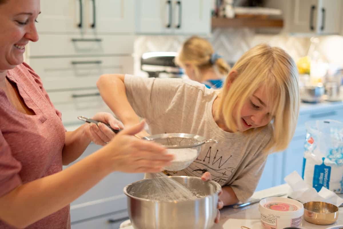 Boy mixing a bowl of whipped cream with mom standing by