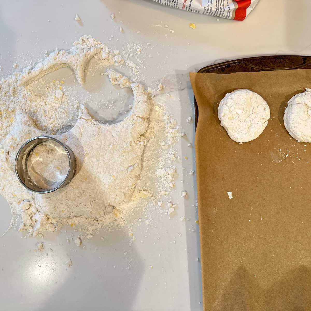 biscuits being cut into circles, and moved to a sheet tray