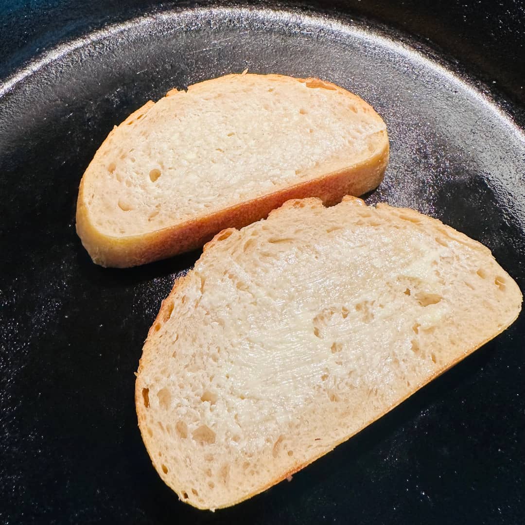 Pan-toasting buttered sourdough on a cast iron skillet