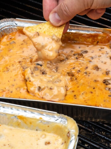 Chip being dipped into a pan of queso