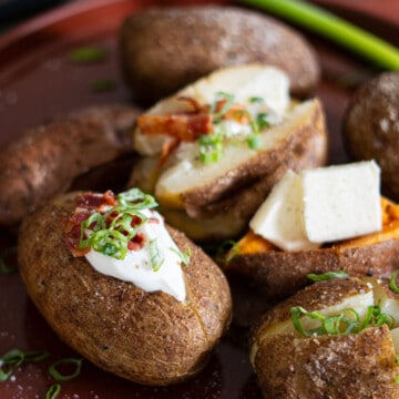 plater of smoked baked potatoes piled with butter, sour cream, green onions and bacon