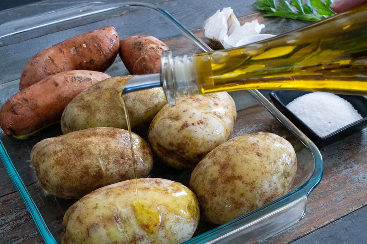 Drizzling olive oil over scrubbed russet potatoes before smoking