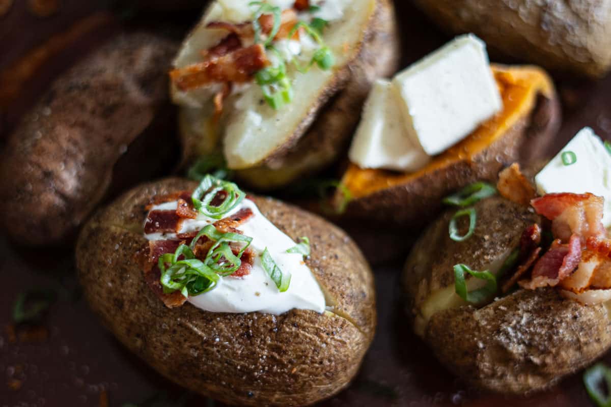 Smoked baked potatoes with crispy salted skin on a wooden board
