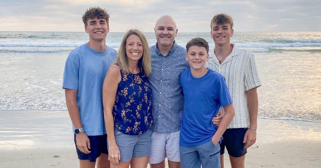 The Joe Kukula family stands beachside on a family vacation and talk in the story about their Tabor College experience