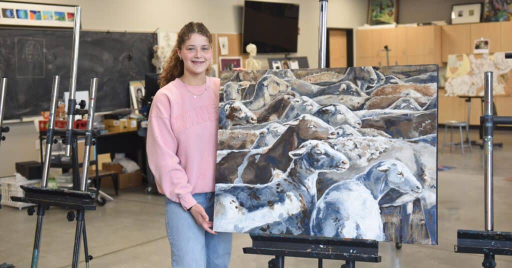 Gracie Rankin stands with her painting in the Tabor studio