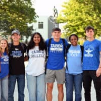A group of six students stand in front of the Shari Flaming Center for the Arts on the Tabor College campus in a admissions photoshoot