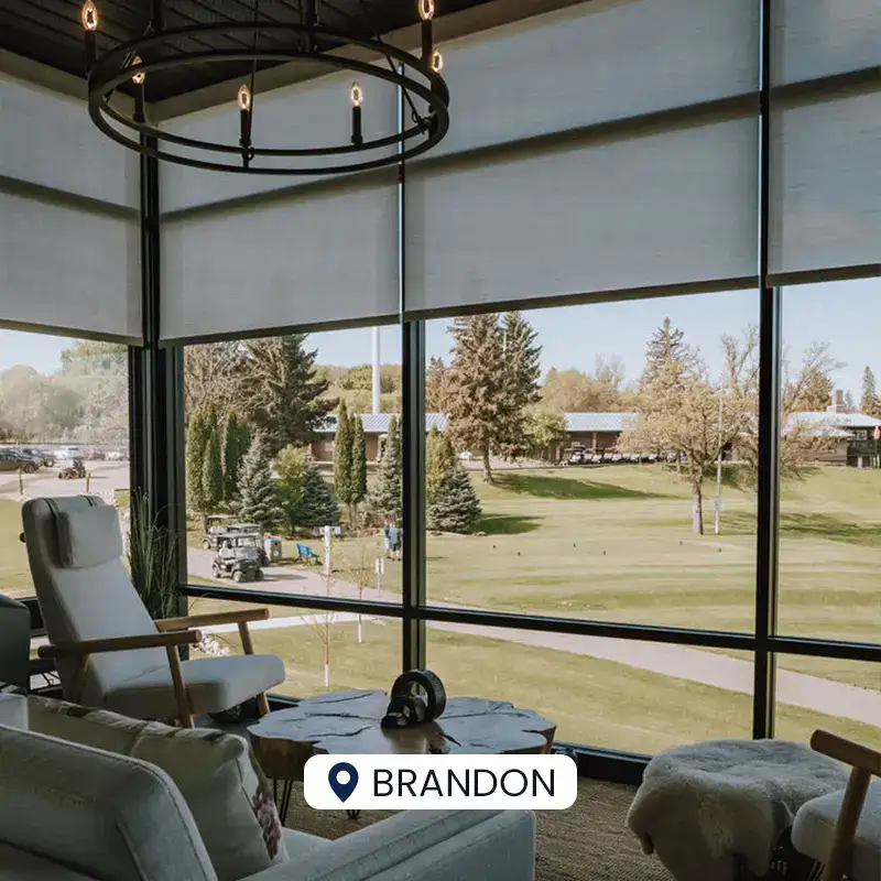 Bright indoor lounge with large windows overlooking a golf course and lush greenery.