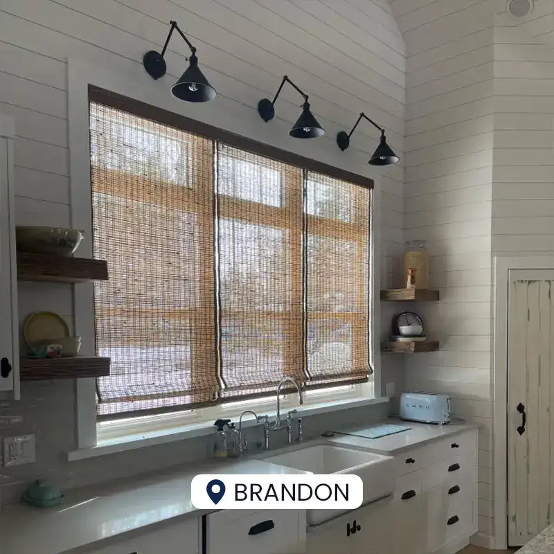 Bright kitchen featuring bamboo window shades, white cabinetry, and black wall-mounted lamps for a warm, inviting atmosphere.