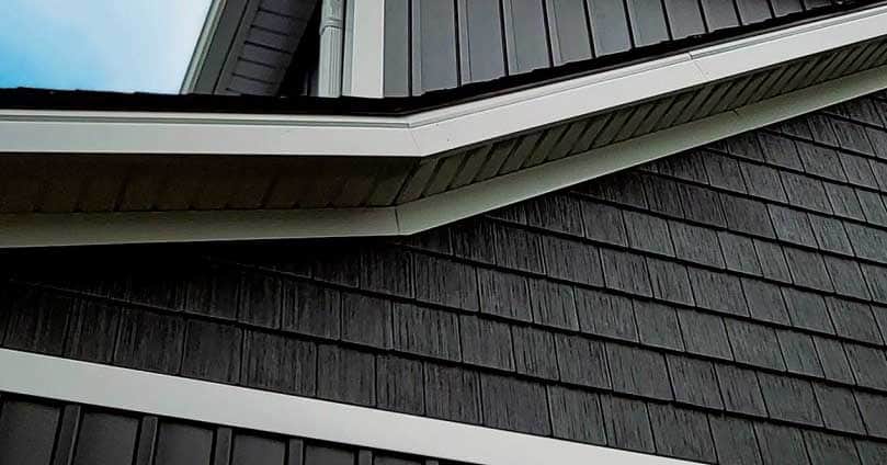 Modern black and grey building exterior with layered siding and trim details.