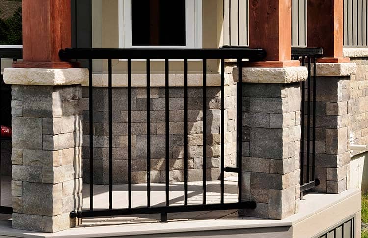 Black metal porch railing with stone pillar supports for enhanced safety and style.
