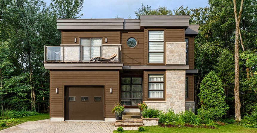 Modern two-story residential home featuring a balcony, large windows, and stone exterior accents.